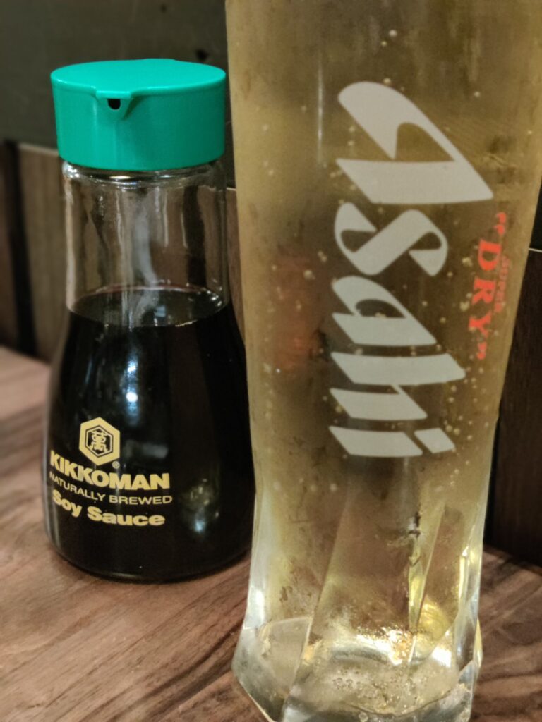 A glass of Asahi beer next to Kikkoman Soy Sauce