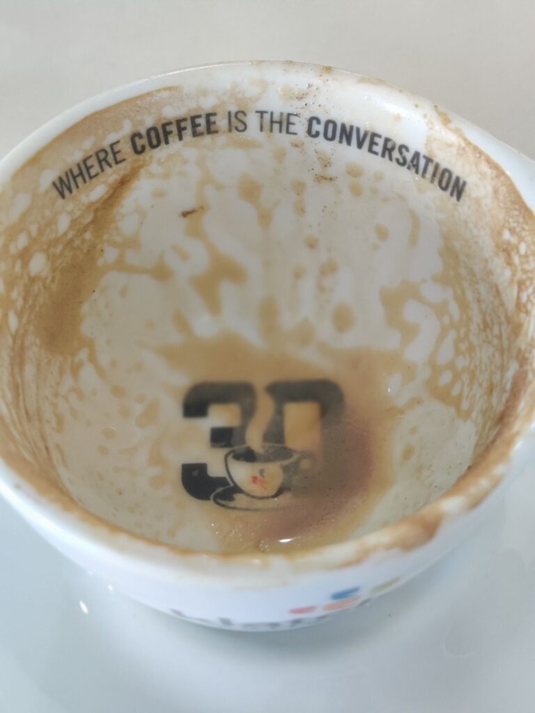 An empty coffee mug formerly containing a Cappuccino.