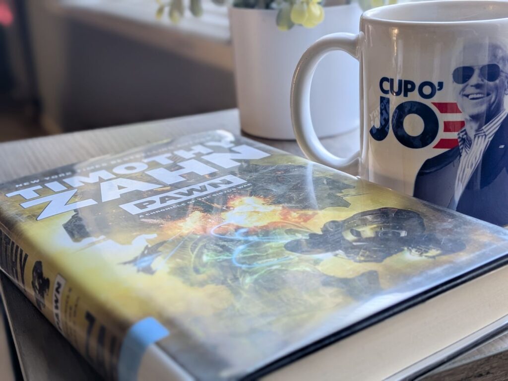Pawn by Timothy Zahn beside a mug and a fake plant