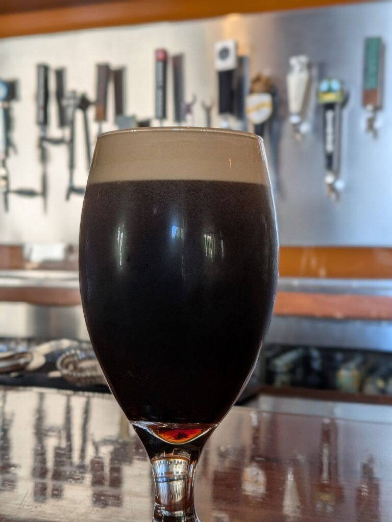 a glass of beer on a bar table in front of taps